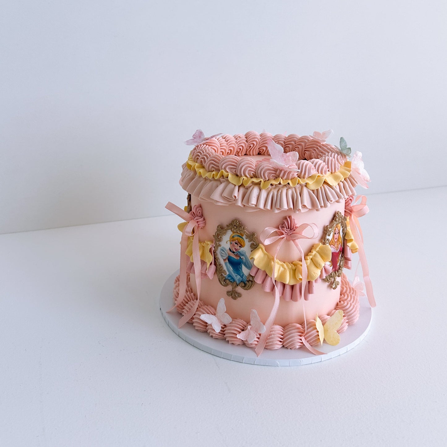 Pink decorative Princess cake with floral and butterfly designs on a white background