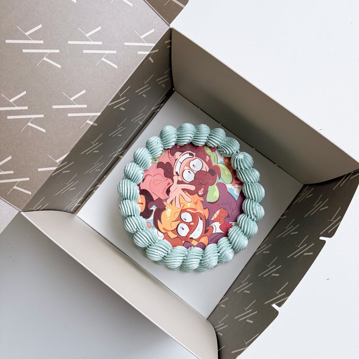 Decorative cake with colorful design in a patterned box on a white background