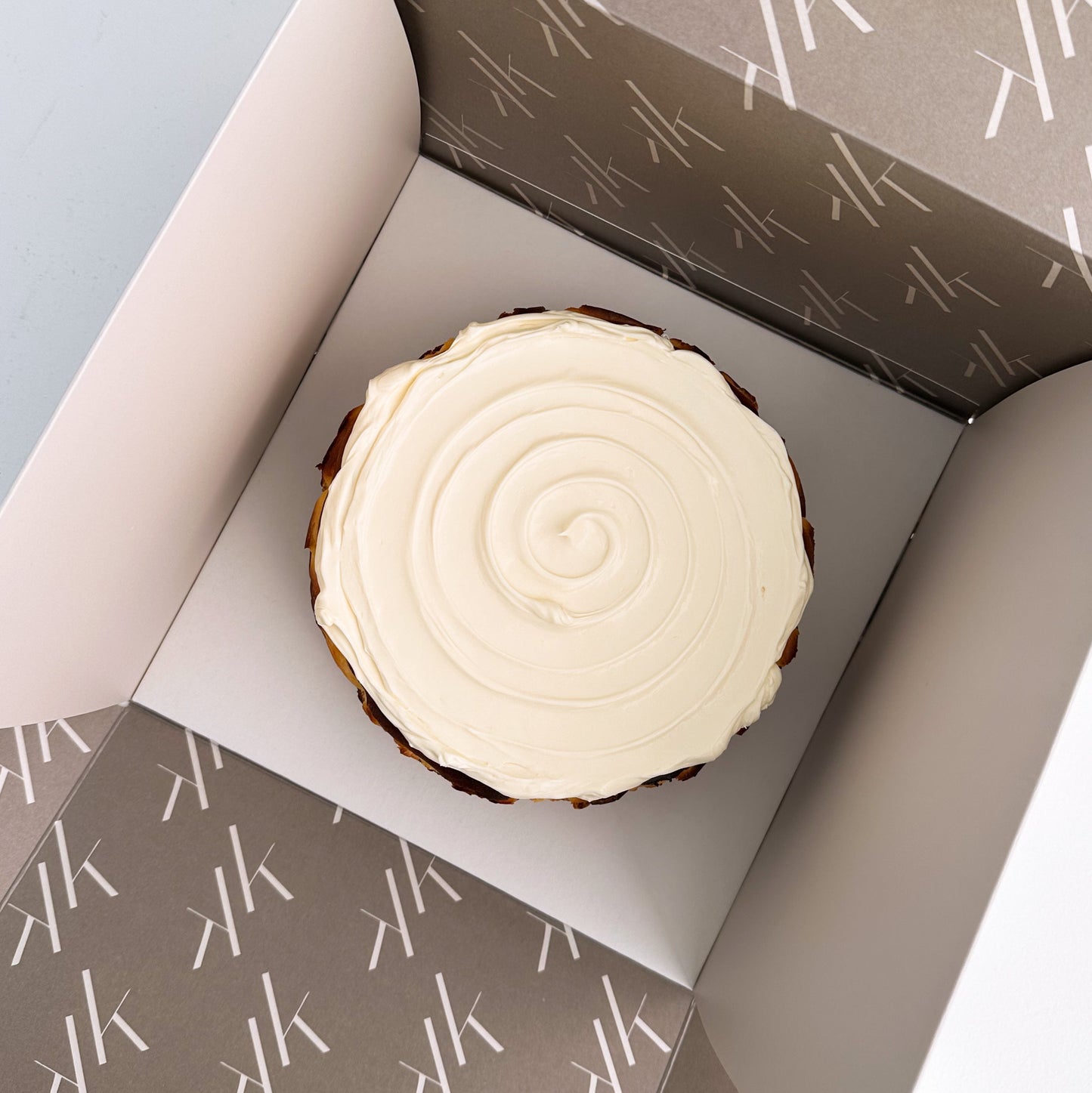 Basque cheesecake in a branded box with a neutral background