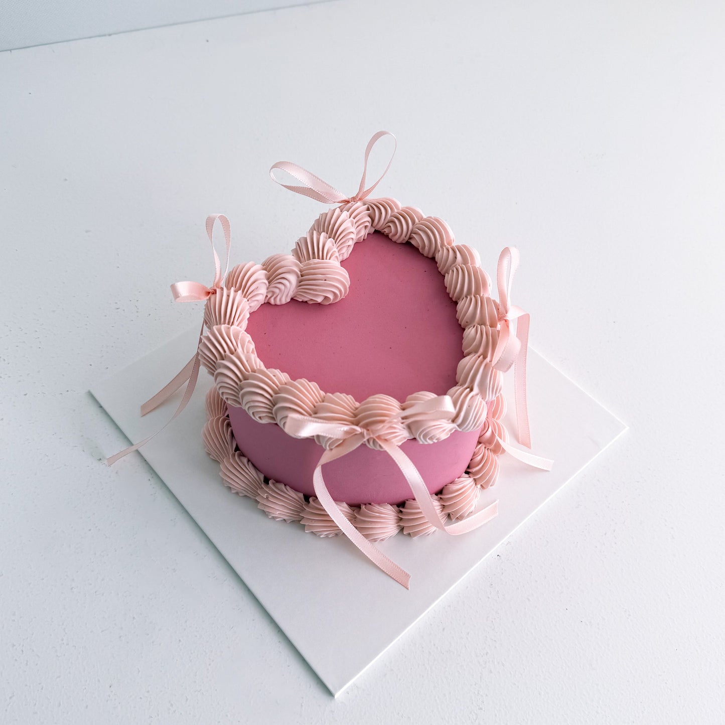 Pink cake with decorative ribbons on a white surface