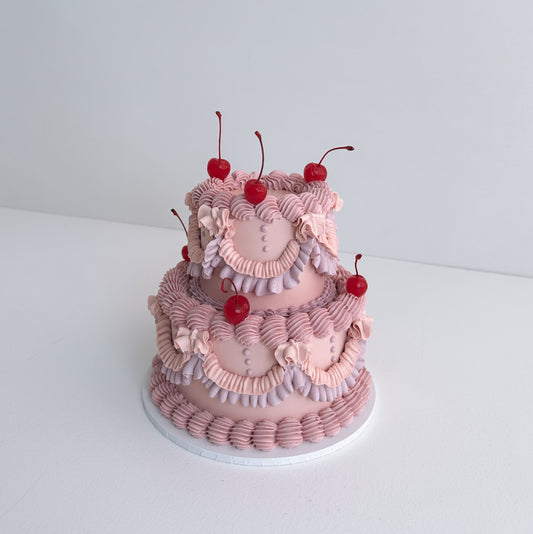 Two-tiered pink cake with cherry decorations on a white background