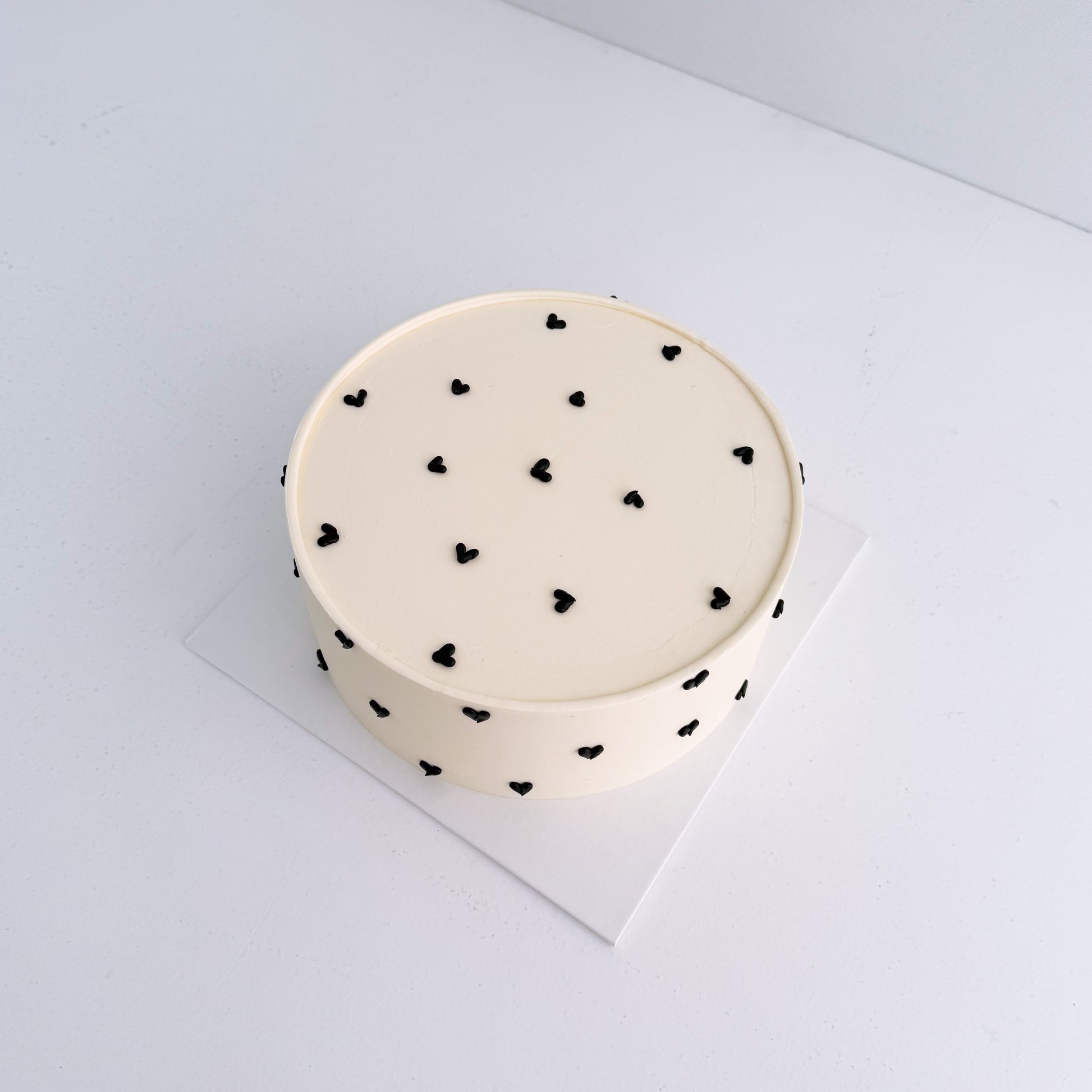 Round cake with black heart patterns on a white background