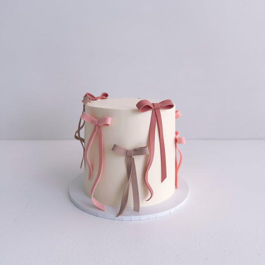 Small cake with decorative ribbons on a white background