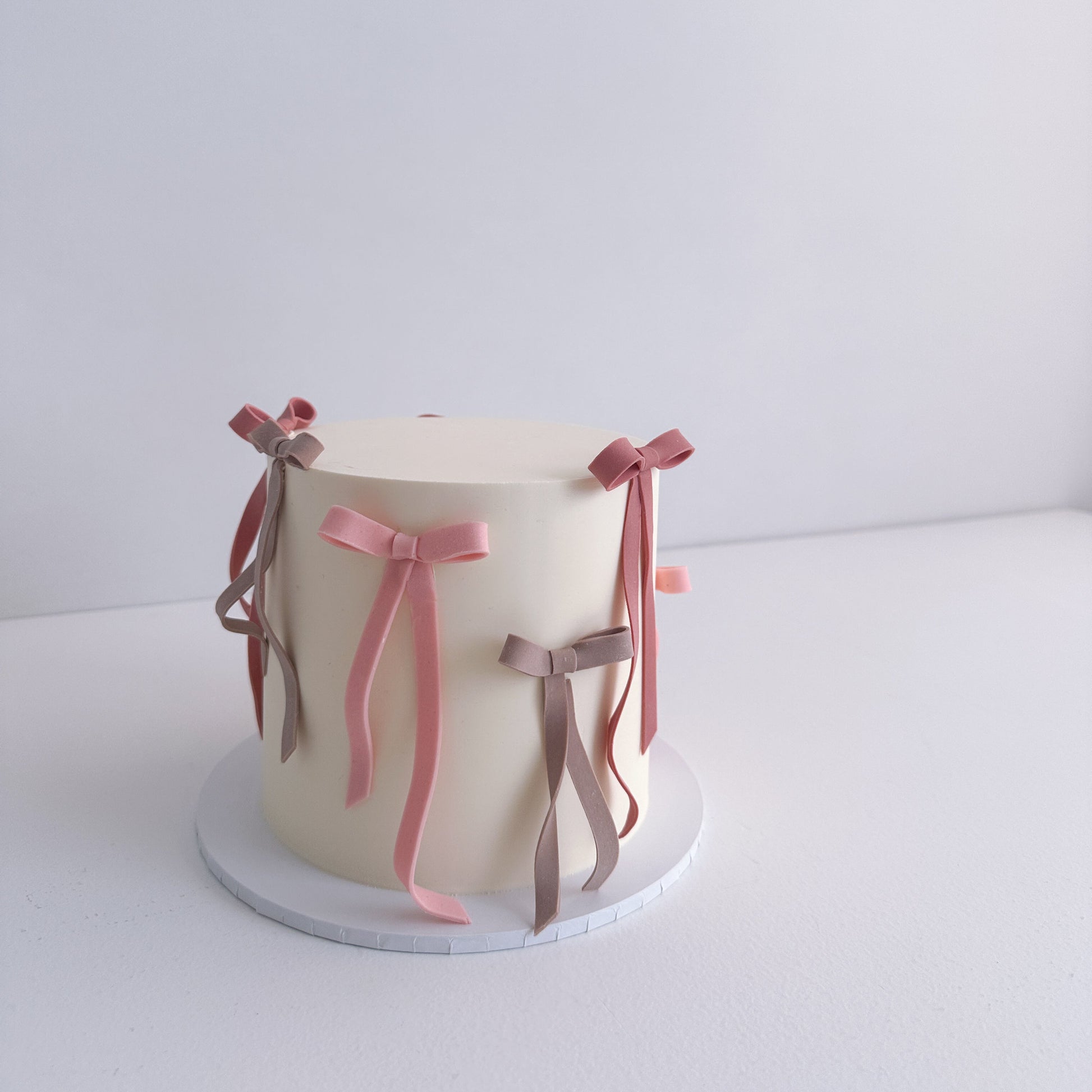Small cake with decorative ribbons on a white background