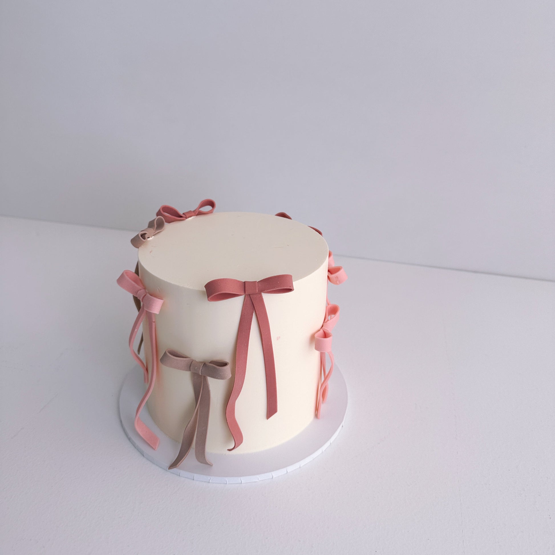 Small round cake decorated with pink ribbons on a white background