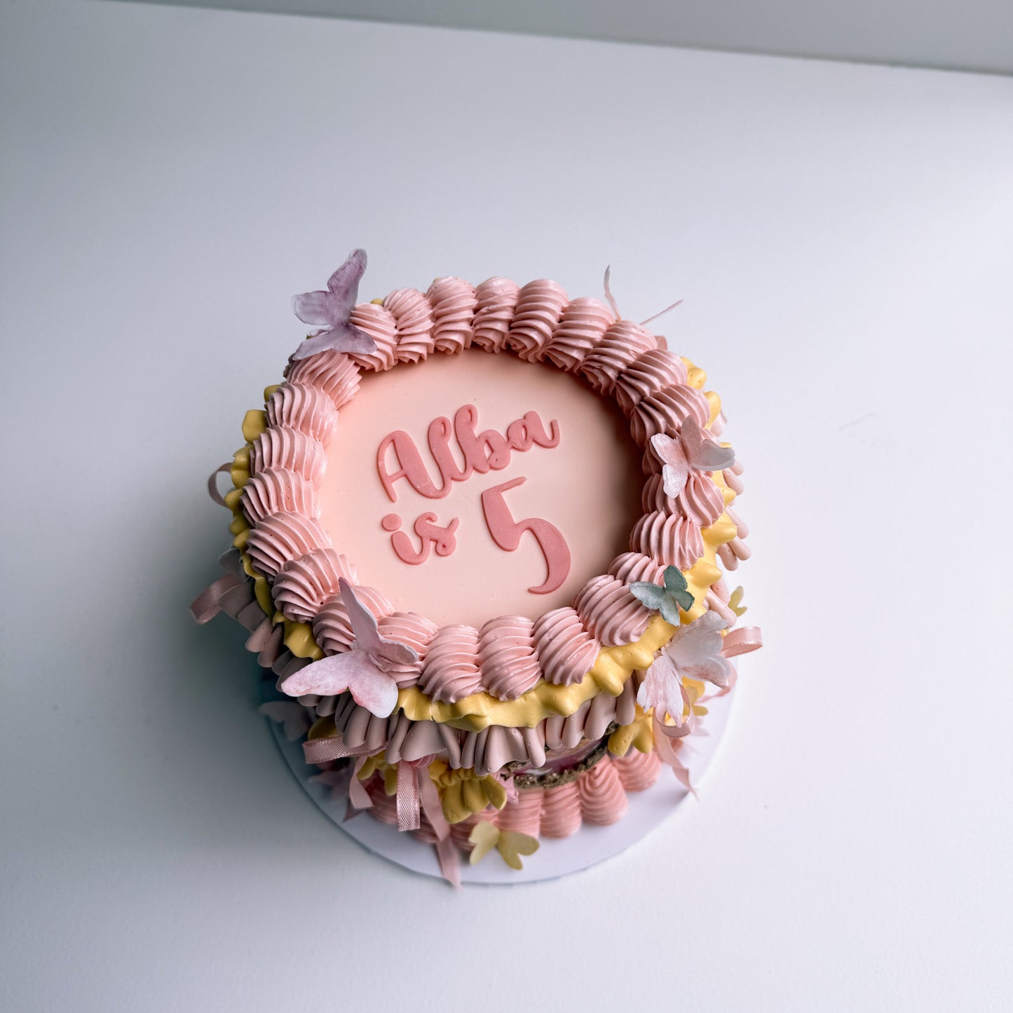 Decorative cake with pink and yellow icing on a white surface auckland cake princess 