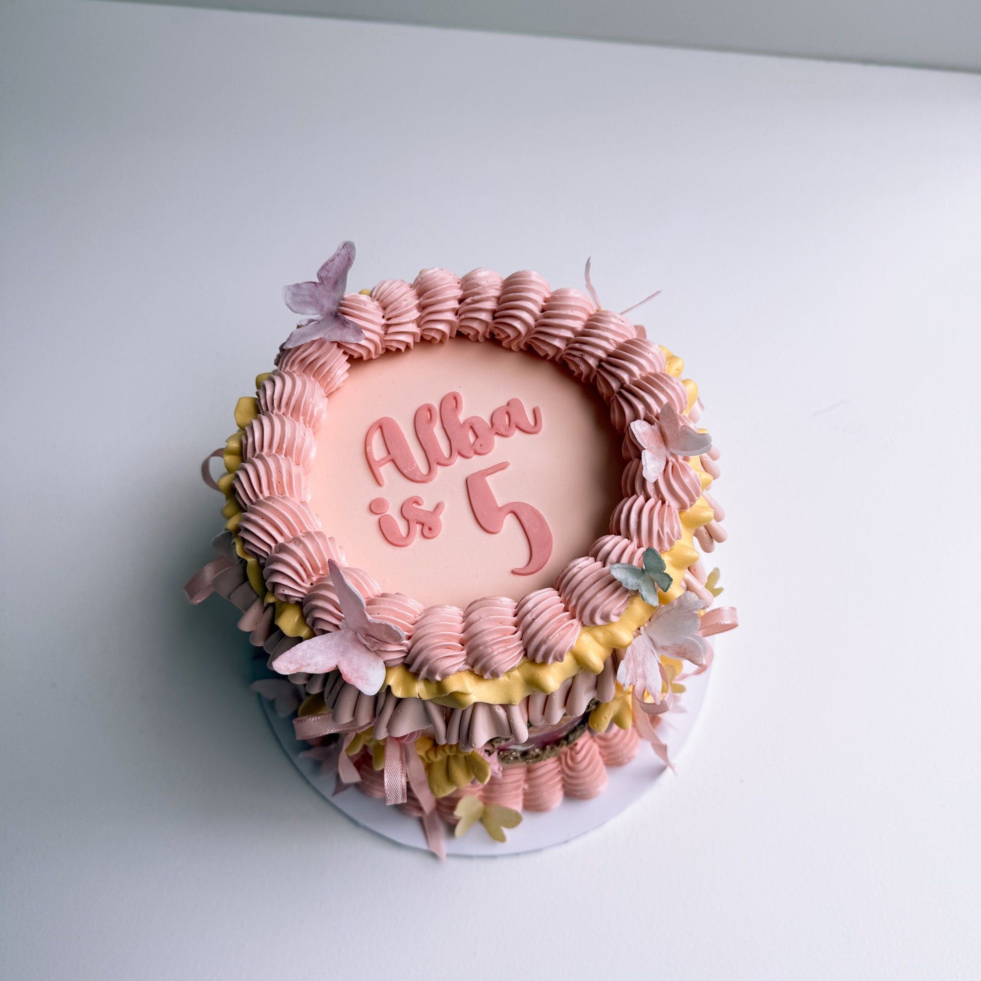 Decorative cake with pink and yellow icing on a white surface auckland cake princess 