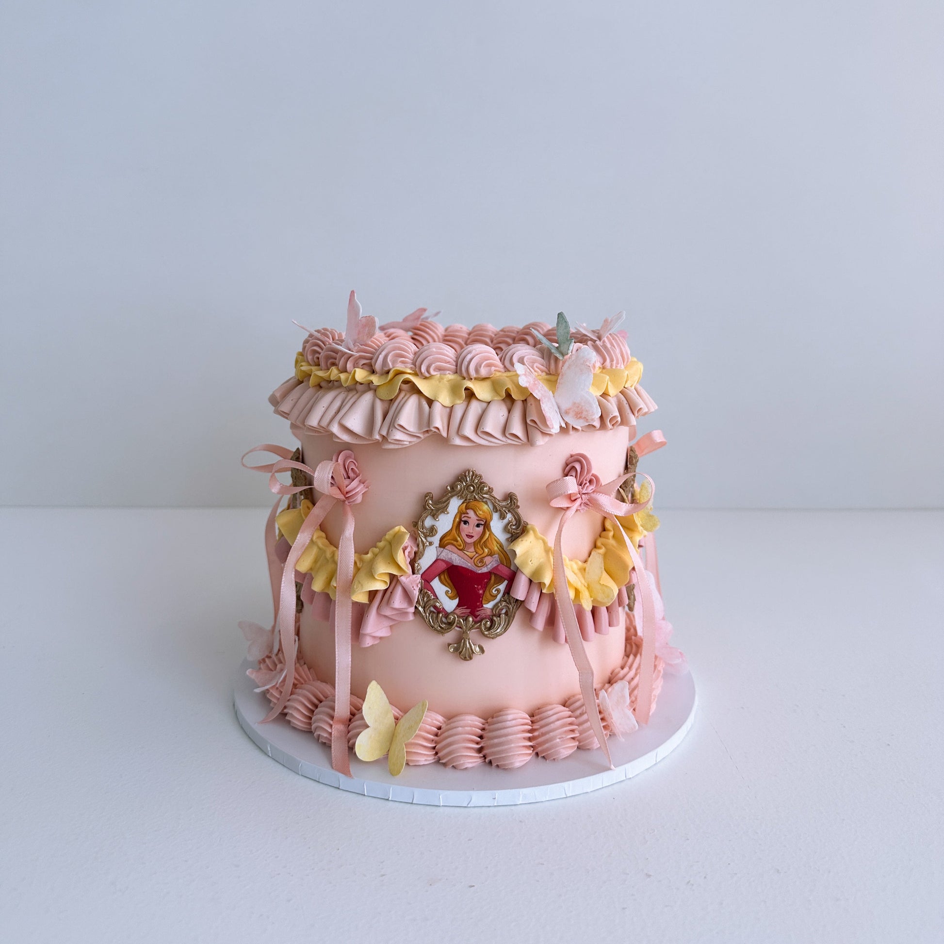 Decorative Princess cake with pink ruffles and a central emblem on a white background